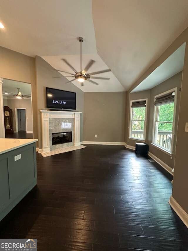 1305 Lake Forest Ln, Mcdonough, GA 30253 - unfurnished living room with a ceiling fan, vaulted ceiling, baseboards, a premium fireplace, and dark wood-type flooring