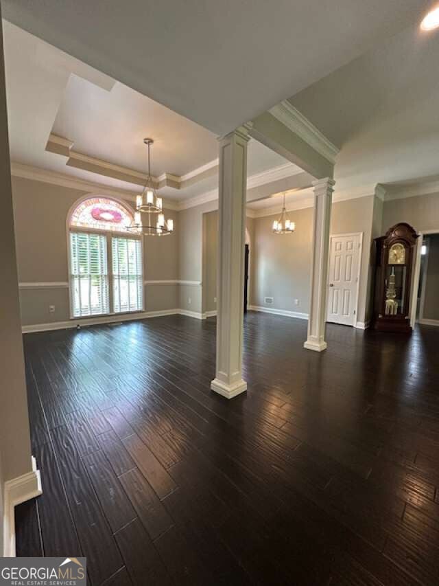 1305 Lake Forest Ln, Mcdonough, GA 30253 - unfurnished living room with a chandelier, a tray ceiling, ornate columns, baseboards, and hardwood / wood-style floors