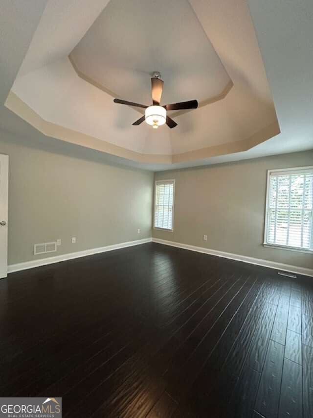 1305 Lake Forest Ln, Mcdonough, GA 30253 - empty room with a raised ceiling, a ceiling fan, baseboards, and dark wood-type flooring