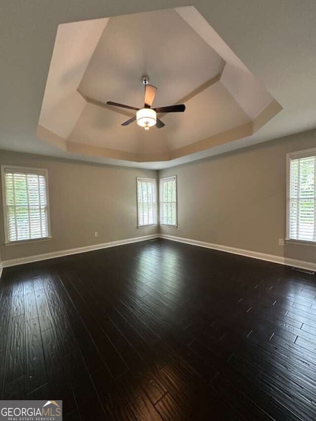 1305 Lake Forest Ln, Mcdonough, GA 30253 - empty room with a raised ceiling, baseboards, and dark wood-style floors