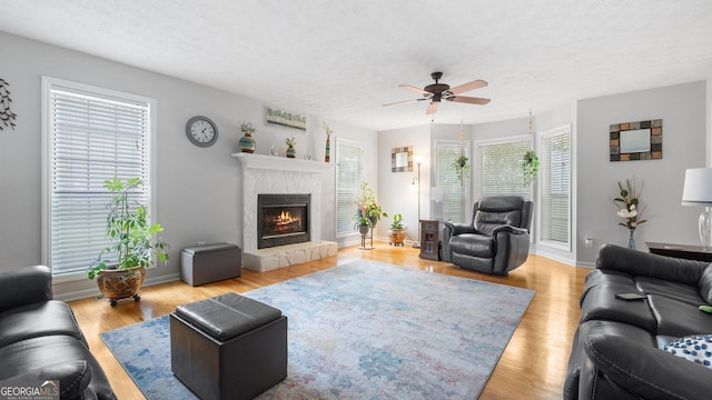 2675 Springside Ct, Douglasville, GA 30135 - living area with ceiling fan, a fireplace, a textured ceiling, light wood-style flooring, and baseboards