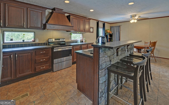 484 Tb Thornton Dr, Hartwell, GA 30643 - kitchen with stainless steel electric range, premium range hood, a breakfast bar area, dark countertops, and crown molding