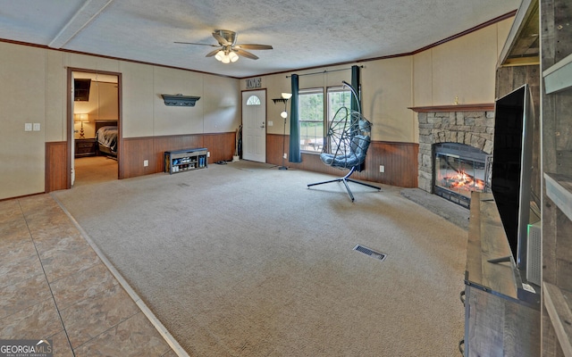 484 Tb Thornton Dr, Hartwell, GA 30643 - unfurnished living room featuring wainscoting, ornamental molding, a ceiling fan, a stone fireplace, and wooden walls