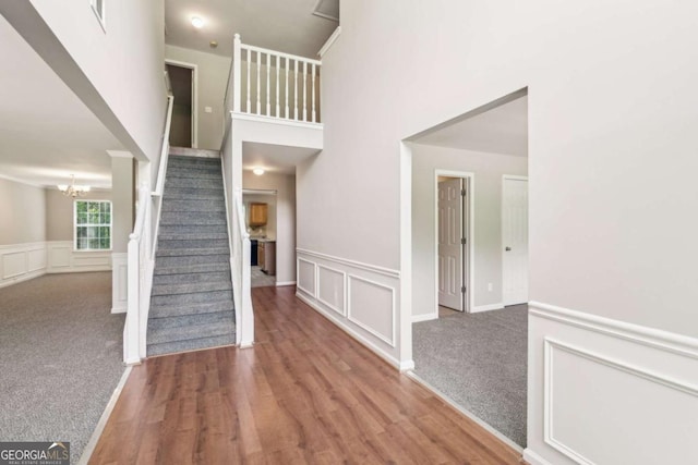 2896 Chilhowee Dr, Atlanta, GA 30331 - staircase featuring a chandelier, a wainscoted wall, a decorative wall, wood finished floors, and a towering ceiling