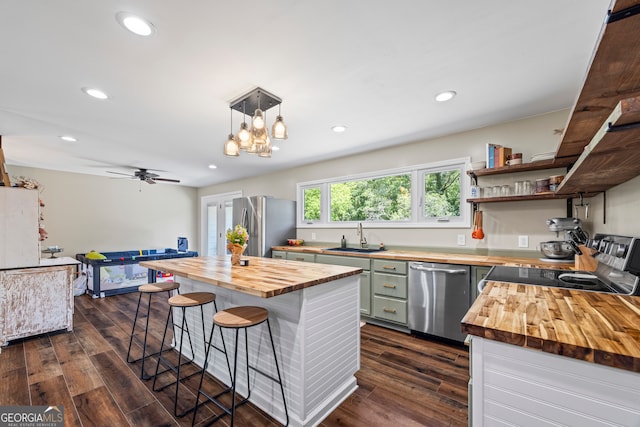 kitchen with wooden counters, appliances with stainless steel finishes, a sink, a kitchen bar, and dark wood finished floors