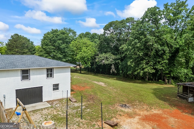 view of grassy yard featuring view of wooded area