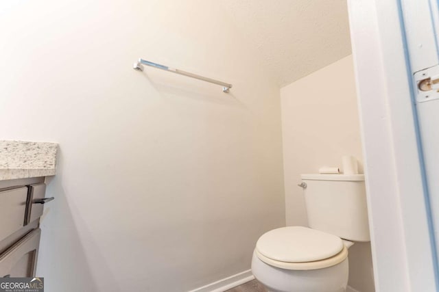 bathroom featuring baseboards, toilet, and vanity