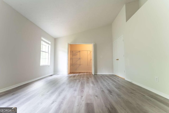 empty room with lofted ceiling, wood finished floors, and baseboards
