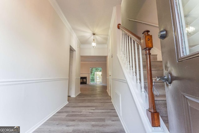 stairway featuring crown molding, wood finished floors, and baseboards