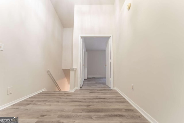 corridor featuring an upstairs landing, wood finished floors, and baseboards