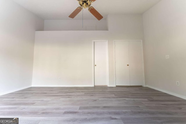 unfurnished bedroom featuring wood finished floors, baseboards, and a ceiling fan
