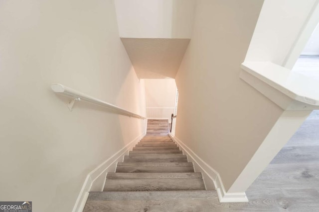 staircase featuring wood finished floors and baseboards