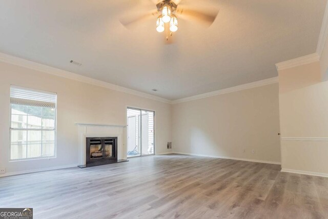 unfurnished living room with wood finished floors, ornamental molding, a glass covered fireplace, ceiling fan, and baseboards