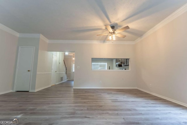 unfurnished living room featuring a ceiling fan, crown molding, wood finished floors, and baseboards