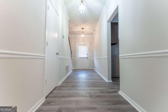 hallway featuring ornamental molding, wood finished floors, and baseboards