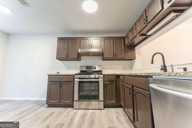 kitchen with stainless steel appliances, under cabinet range hood, light countertops, and light wood finished floors