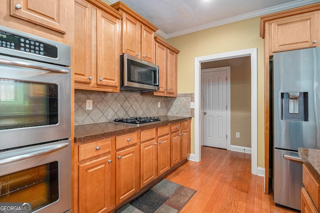 145 Windward Hls, Mcdonough, GA 30253 - kitchen featuring appliances with stainless steel finishes, crown molding, light wood finished floors, decorative backsplash, and dark stone countertops