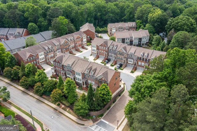 aerial view of property and surrounding area featuring a heavily wooded area and nearby suburban area