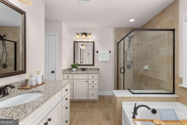 full bath featuring a shower stall, wood finished floors, two vanities, recessed lighting, and a tub