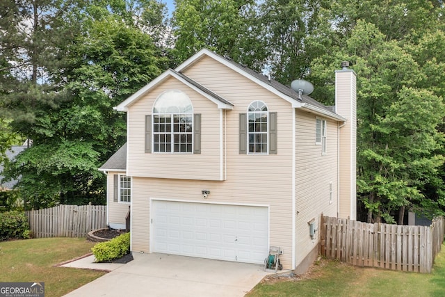 view of front of home with concrete driveway, a chimney, an attached garage, and view of wooded area