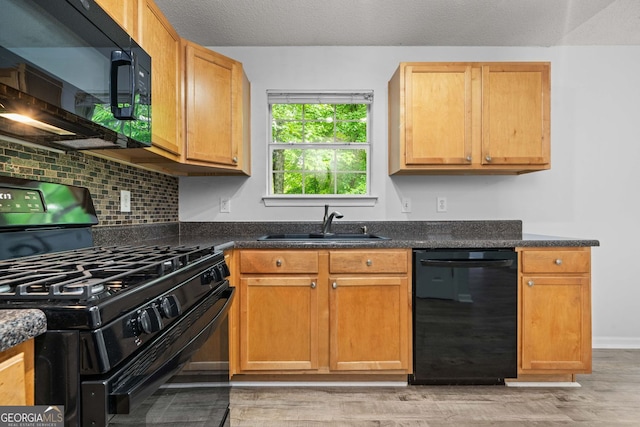 kitchen with black appliances, a sink, light wood finished floors, decorative backsplash, and baseboards
