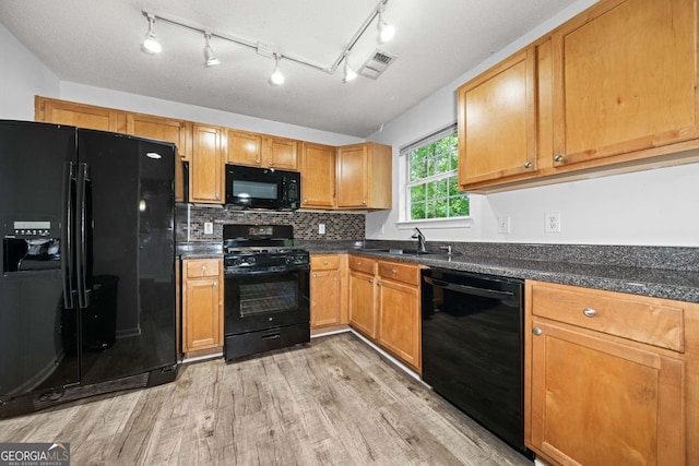kitchen with black appliances, a sink, light wood-type flooring, dark countertops, and decorative backsplash
