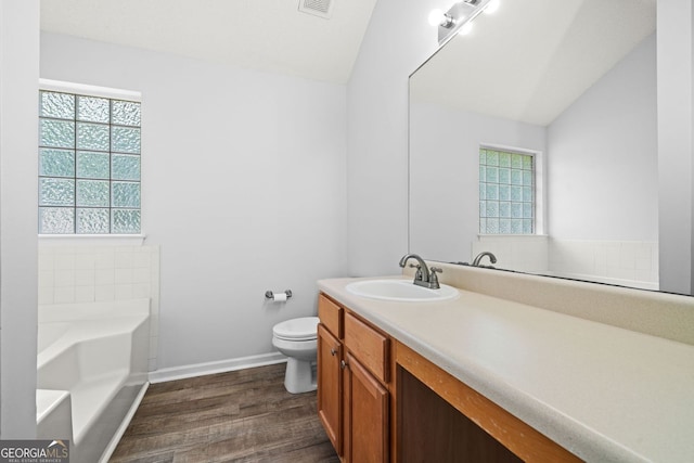 full bath featuring lofted ceiling, toilet, a garden tub, vanity, and wood finished floors