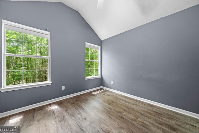 spare room featuring lofted ceiling, wood finished floors, baseboards, and ceiling fan
