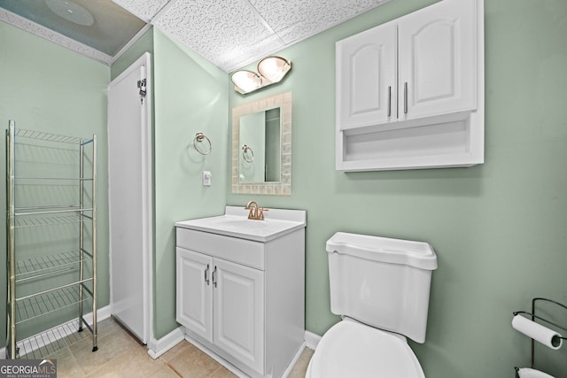 bathroom featuring toilet, vanity, baseboards, tile patterned flooring, and a paneled ceiling