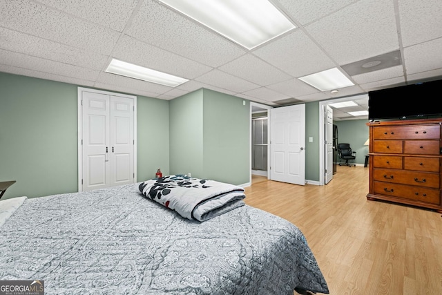 bedroom featuring light wood-style floors, a paneled ceiling, and a closet