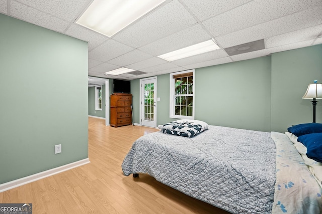 bedroom with a paneled ceiling, wood finished floors, and baseboards
