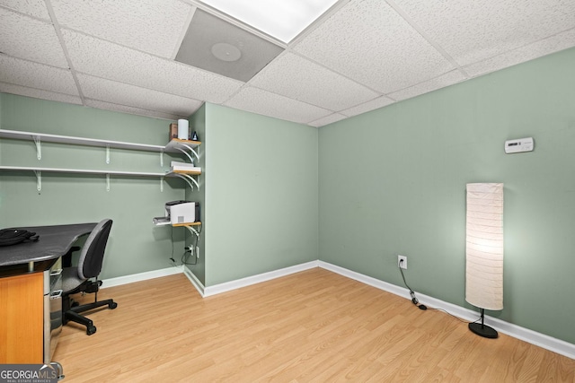 home office with light wood-type flooring, a drop ceiling, and baseboards