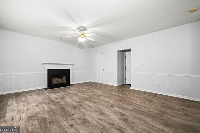 unfurnished living room with ceiling fan, wood finished floors, a fireplace with flush hearth, and baseboards