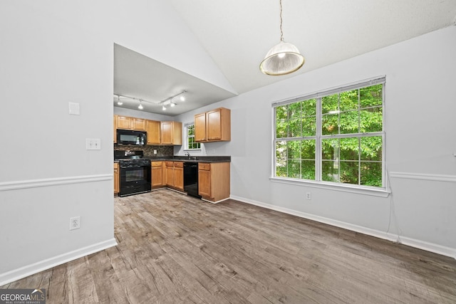 kitchen featuring black appliances, dark countertops, lofted ceiling, and baseboards