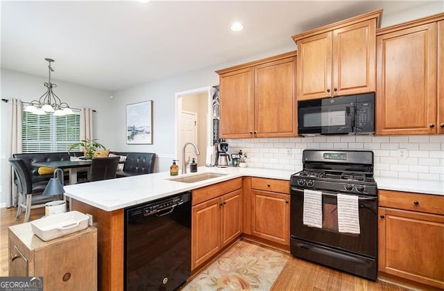 59 Creekside Blf, Hiram, GA 30141 - kitchen with black appliances, a sink, a chandelier, a peninsula, and light wood-style flooring