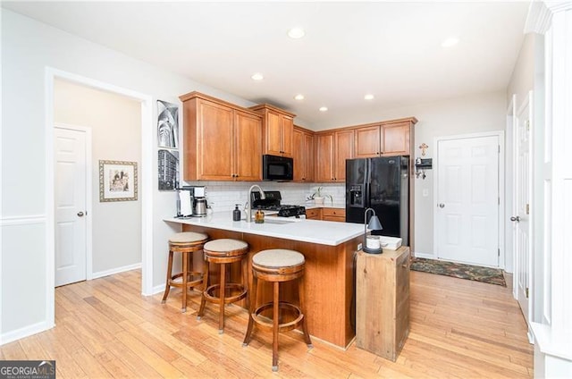 59 Creekside Blf, Hiram, GA 30141 - kitchen with black appliances, a peninsula, light wood-style floors, light countertops, and tasteful backsplash