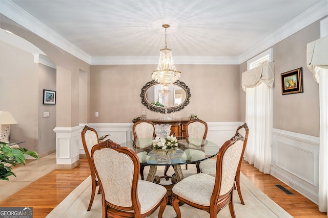 127 Courts Of Hampton, Hampton, GA 30228 - dining area featuring arched walkways, a chandelier, light wood-style floors, crown molding, and a wainscoted wall