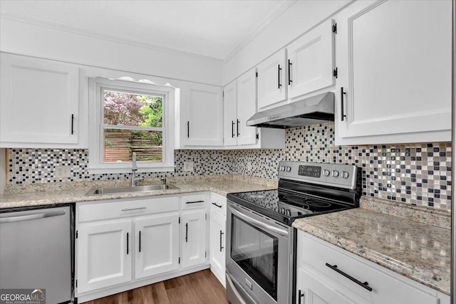 kitchen with appliances with stainless steel finishes, range hood, a sink, crown molding, and white cabinetry