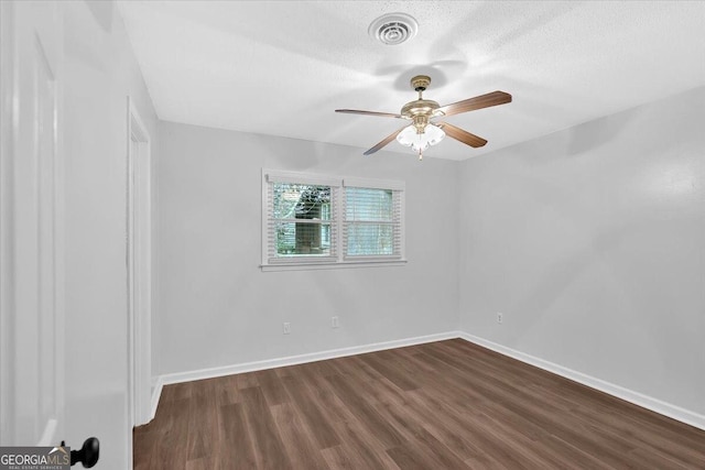 empty room featuring dark wood-type flooring, ceiling fan, baseboards, and a textured ceiling