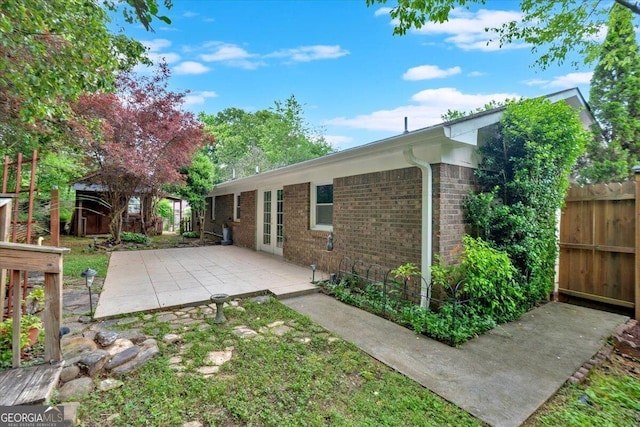 back of house featuring fence, a patio, and brick siding