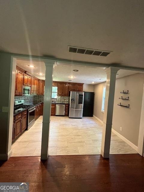 1221 Martin Nash Rd SW, Lilburn, GA 30047 - kitchen featuring stainless steel appliances, ornate columns, dark countertops, and backsplash