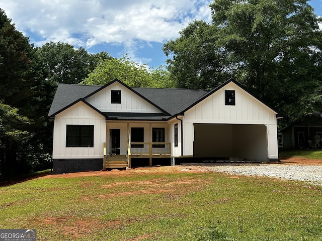 modern farmhouse style home with covered porch, roof with shingles, a front lawn, and board and batten siding