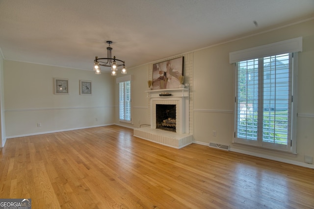 12 Riverview Rd SE, Rome, GA 30161 - unfurnished living room featuring light wood-style flooring, a chandelier, ornamental molding, a brick fireplace, and baseboards