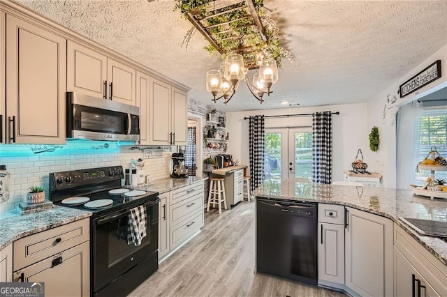 kitchen featuring black appliances, a textured ceiling, light wood finished floors, french doors, and decorative backsplash
