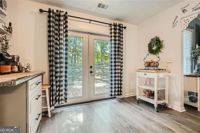 entryway featuring french doors, wood finished floors, baseboards, and a textured ceiling