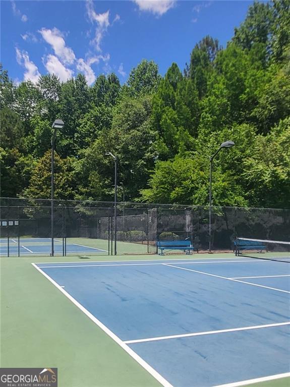 view of tennis court with community basketball court and fence