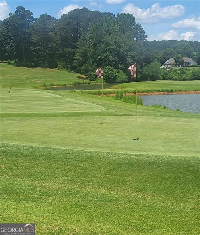 surrounding community featuring a water view, golf course view, a lawn, and a putting area
