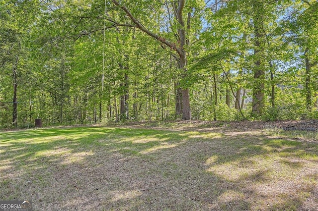 view of grassy yard featuring a view of trees