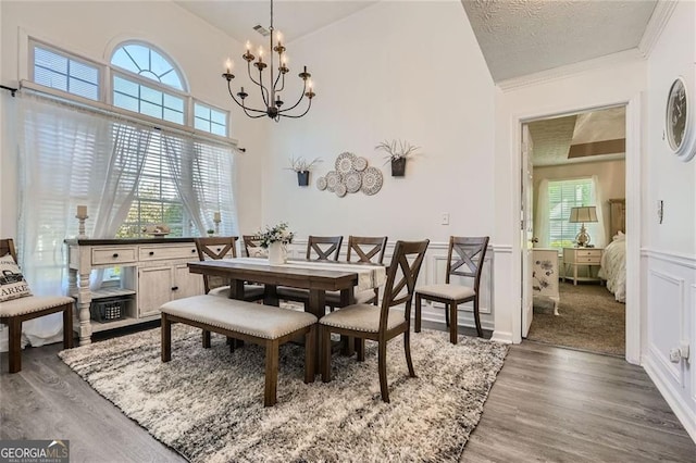 dining room featuring a chandelier, plenty of natural light, wood finished floors, vaulted ceiling, and ornamental molding