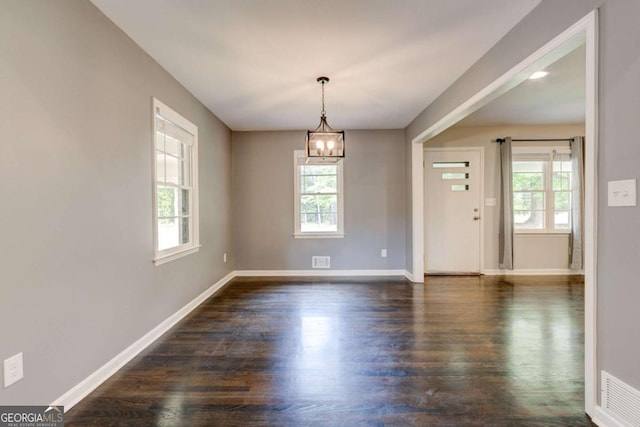 spare room with healthy amount of natural light, baseboards, and a chandelier
